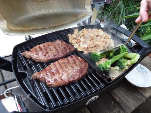 Steaks and stuff cooking on the grill.