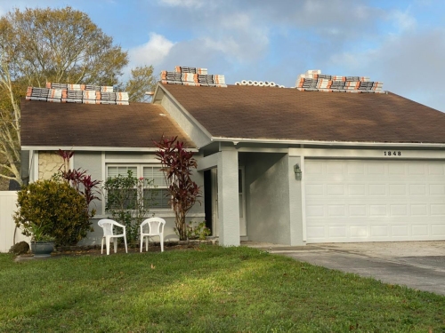 The old roof with shingles and roofing supplies stacked up.