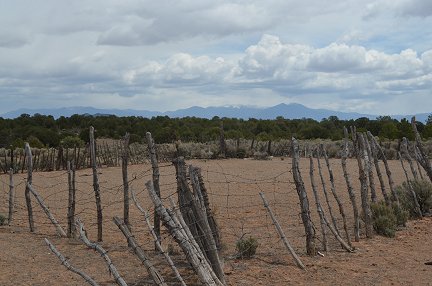 An old corral with snow covered mountains in the background.