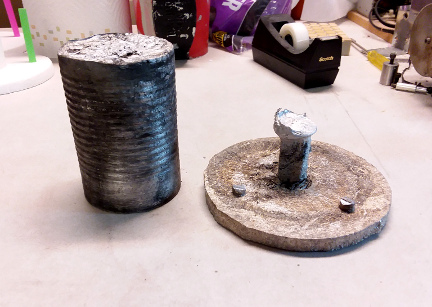 A rough cast aluminum disk and cast rod stock.
